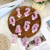 A collection of elegant pink birthday candles numbered 1 through 6 arranged on a wooden platter.
