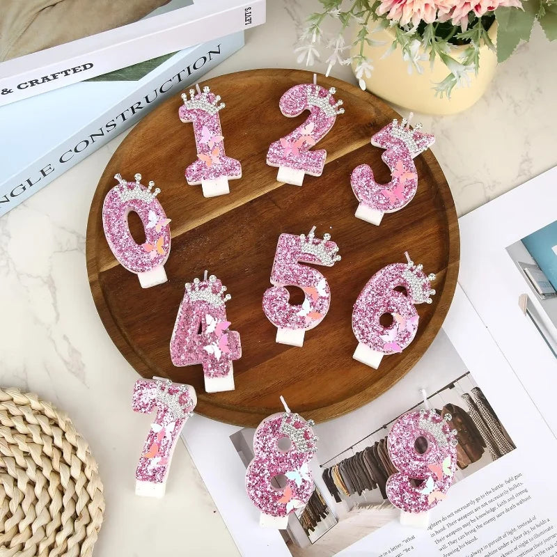 A collection of elegant pink birthday candles numbered 1 through 6 arranged on a wooden platter.