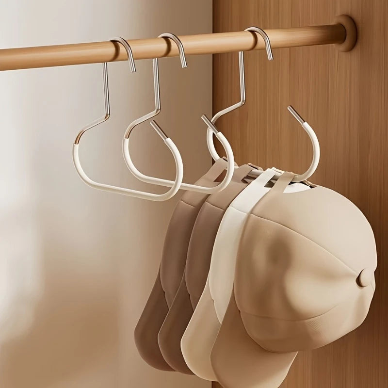 A set of metal hat storage hooks hanging on a wooden rod, with several light beige hats visible below.