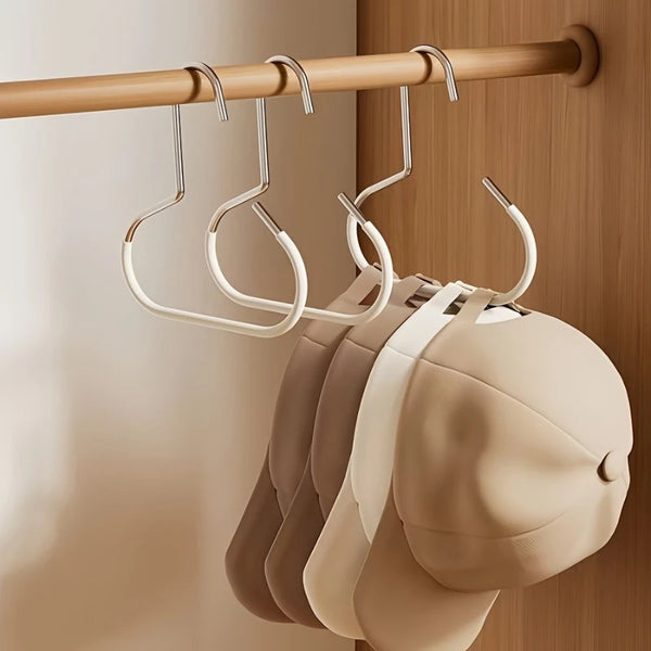 A set of metal hat storage hooks hanging on a wooden rod, with several light beige hats visible below.