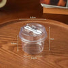 A clear disposable pudding cup with a lid and spoon shown on a wooden surface.