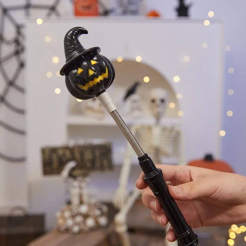 Une main tient une lanterne en bâton noire et lumineuse avec une tête de citrouille sculptée contre un fond blanc.