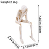 A white resin skeleton skull figurine with elongated limbs and a head, shown against a measurement scale.