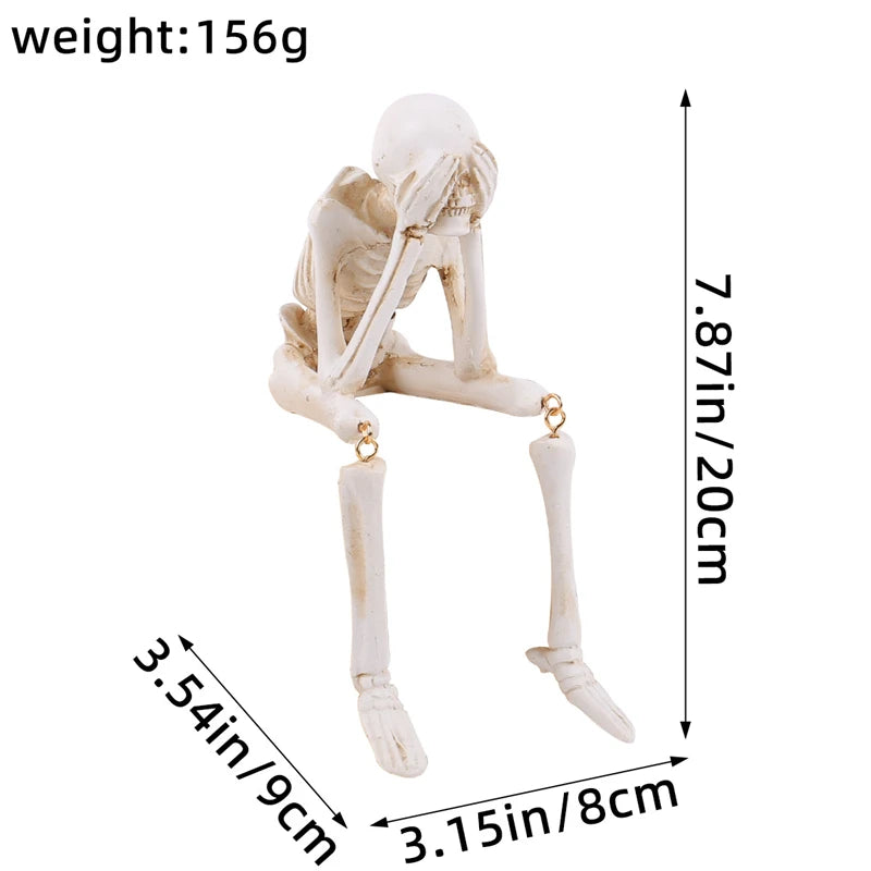 A white resin skeleton skull figurine with elongated limbs and a head, shown against a measurement scale.