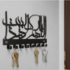 Black Islamic Arabic blessing key holder with hooks and brass keys mounted on a white wall.