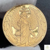A round gold souvenir coin featuring a relief depiction of Saint Michael with wings and a staff.