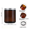 A set of two amber glass candle jars with airtight metal lids shown next to a measurement scale.