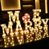 Warm white LED alphabet letter lights spelling out 'MARRY' with a heart accent on a wooden surface.
