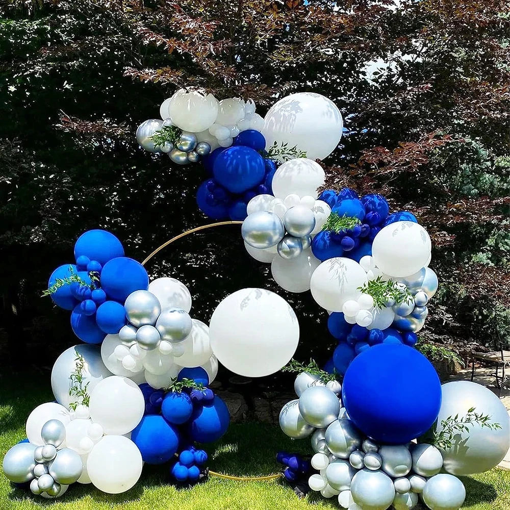 A cluster of round latex balloons in white and blue are arranged on green grass.