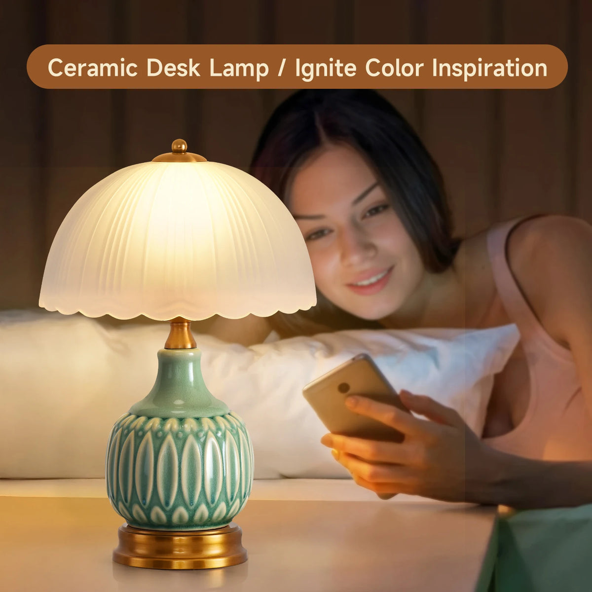 A ceramic desk lamp with a green crackle glaze sits on a table next to a woman using a smartphone.