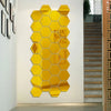 A vertical wall decor piece made of yellow, self-adhesive hexagon mirror stickers mounted on a white wall.