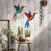 Vibrant metal hummingbird wall art featuring iridescent colors hanging on a light wood panel.
