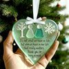 A handcrafted acrylic friendship snowflake Christmas pendant with two silhouette figures is held against a green Christmas tr