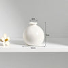 A white ceramic mini vase with a rounded body and a small opening, shown on a white surface.