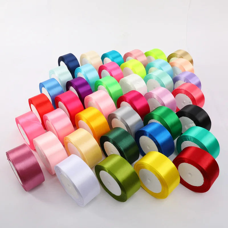 A collection of colorful satin ribbon rolls in various shades including pink, green, yellow, and blue.
