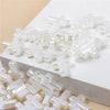 White acrylic cross shape beads scattered on a white surface for DIY jewelry making