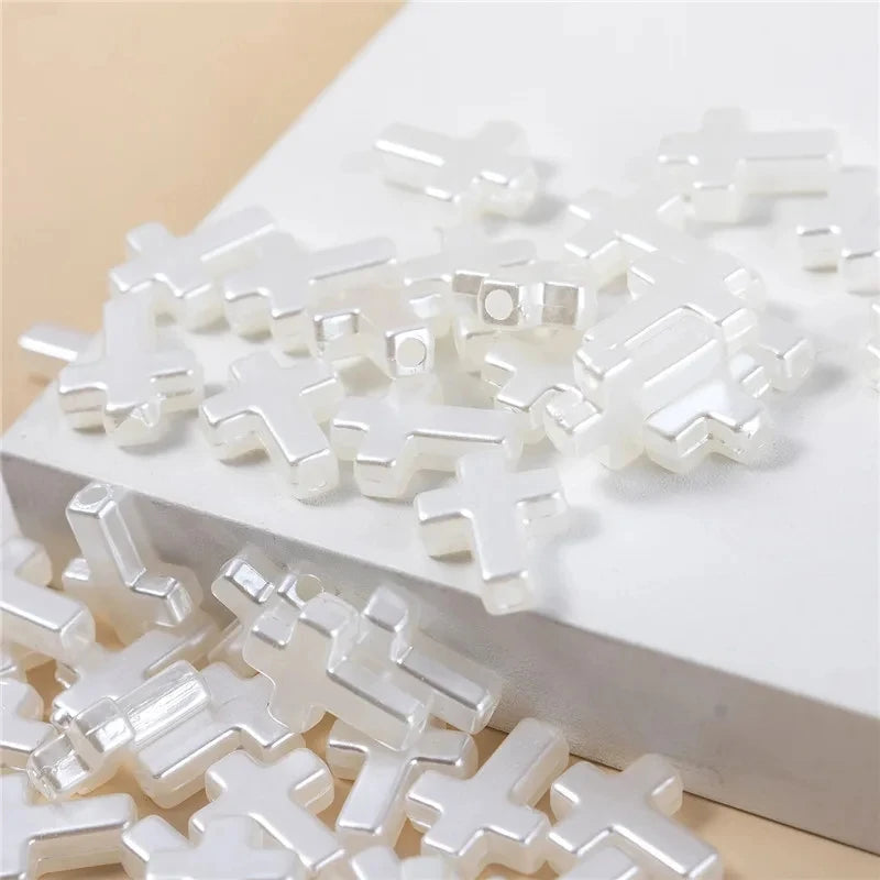 White acrylic cross shape beads scattered on a white surface for DIY jewelry making