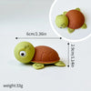 A set of three plastic ocean animal cake toppers: a green whale, an orange octopus, and a brown turtle.