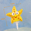 Yellow starfish cake topper with orange dots and a white stem.