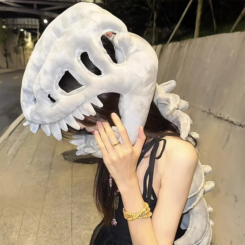 A person wearing a white dinosaur skeleton costume with a head and spine, posing outdoors at night.