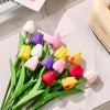 A bouquet of realistic artificial tulips in shades of white, yellow, pink, and purple arranged on a white surface.