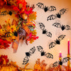 A wall decorated with black bat silhouettes made of autumn leaves and foliage.