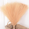 Ramo de pampas seco, esponjoso y de color beige claro, atado con hilo, exhibido en una estera tejida.