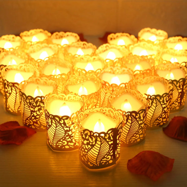 A collection of glowing yellow LED tea light candles in ornate paper lampshades arranged on a wooden surface.
