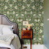 Mur de chambre avec papier peint adhésif bohème floral aux feuilles vertes et fleurs blanches.