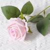 A soft pink artificial rose with green leaves on a white textured background.