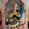 A detailed ball-jointed doll of a princess with blonde hair, elaborate makeup, and a dark purple and white gown.