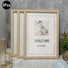 A light wood photo frame with glass panels is displayed against a gray wall, showing a welcome message.