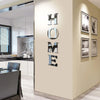 A modern interior wall features silver letter decals spelling out HOME on a beige wall.