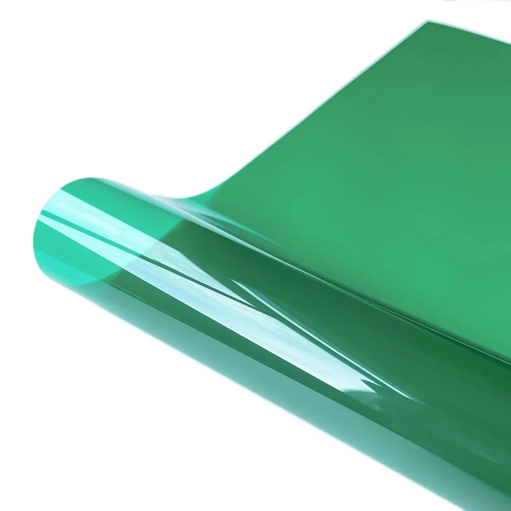 A sheet of green decorative stained glass window film rolled and curved to show its glossy surface.