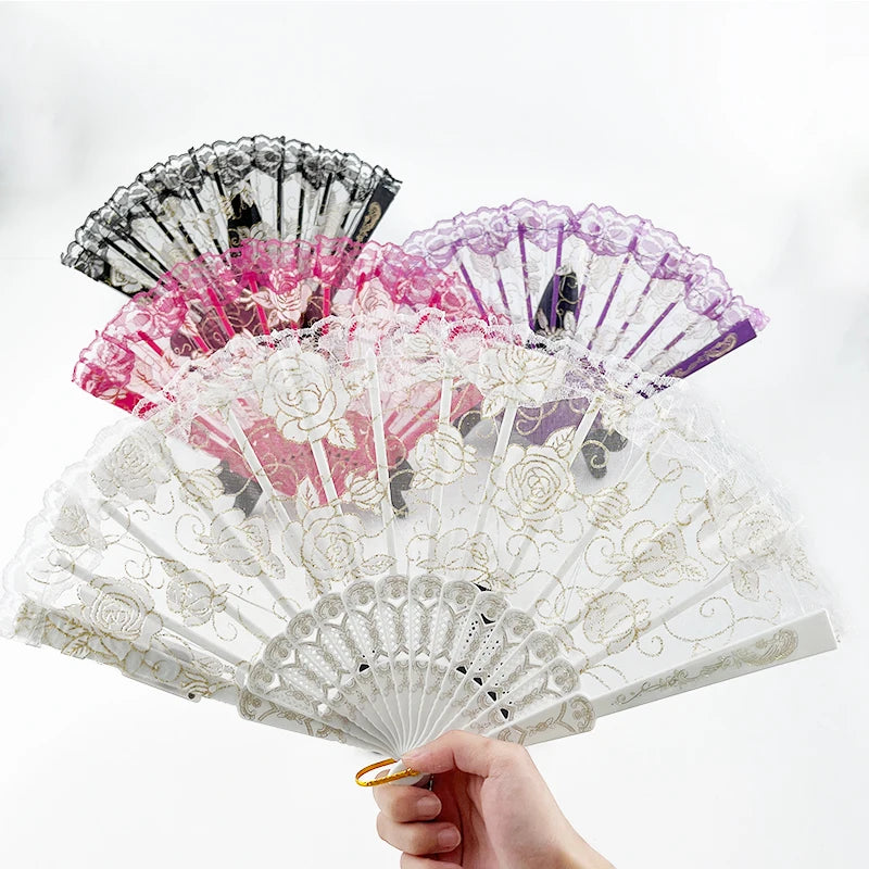 A hand holding an open LED dancing hand fan with pink and purple floral patterns.