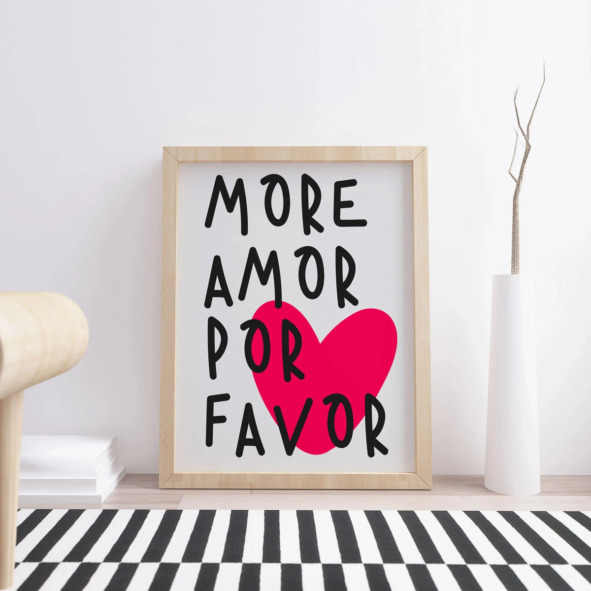A framed canvas print featuring the text More Amor Por Favor in black and bright pink on a white background.