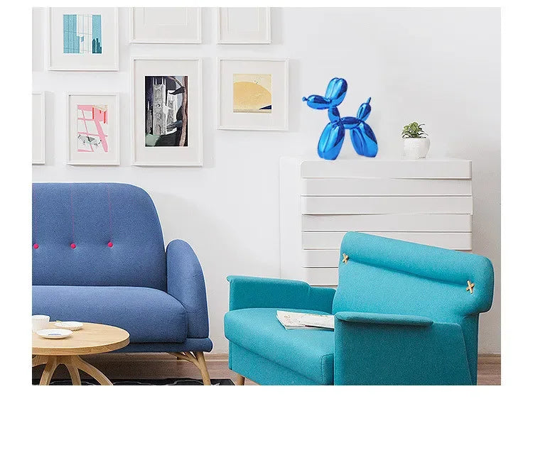 A teal blue resin balloon dog sculpture decor item displayed on a white cabinet with framed art.