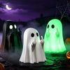 A white ghost figurine with a sassy hand gesture stands in front of glowing green and black ghosts under a purple night sky.
