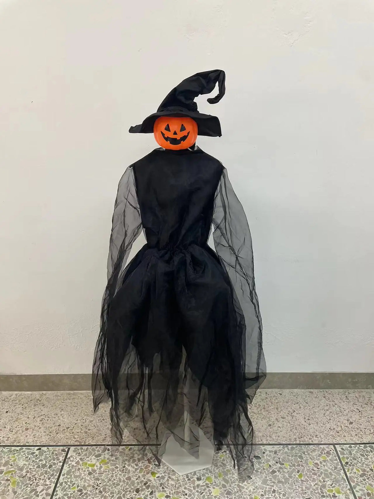 A black witch hat with pointed ears and an orange carved pumpkin face decoration.