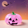 A bright pink Halloween pumpkin stress ball with a carved face sits against a purple and orange background with bats flying.