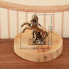 A solid copper horse figurine standing on a wooden base, depicting a dynamic pose.