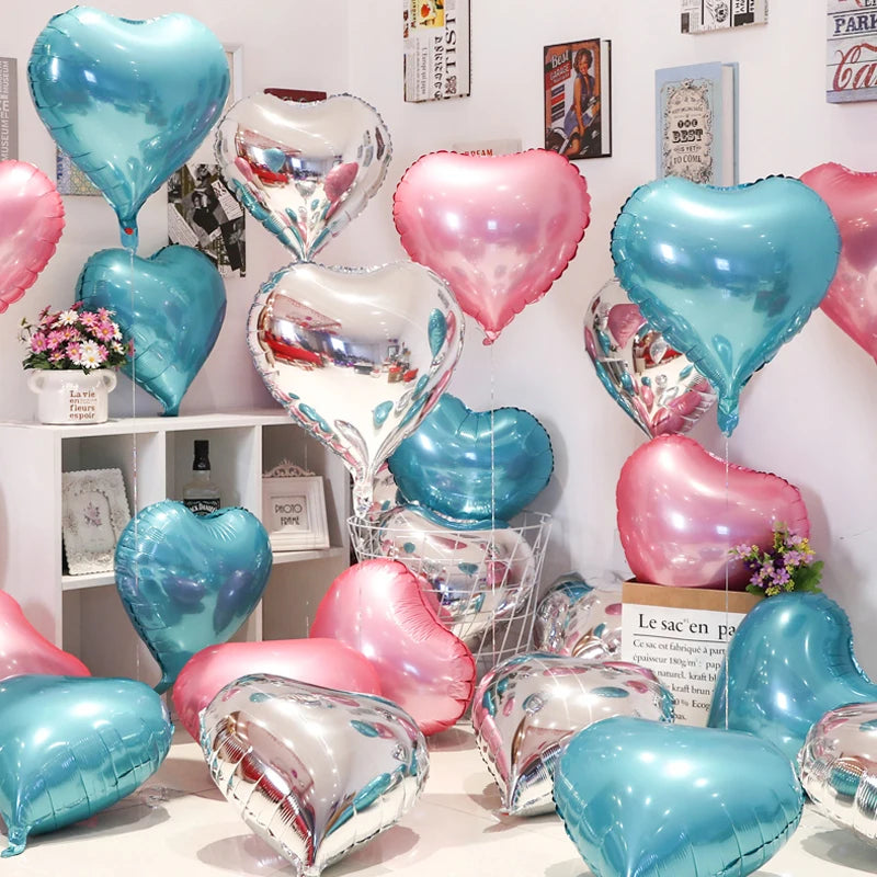A collection of iridescent heart-shaped foil balloons in shades of blue, pink, and silver are displayed on a white surface.