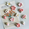 A set of 12 pink and white kawaii flower decorative fridge magnets arranged on a white card.