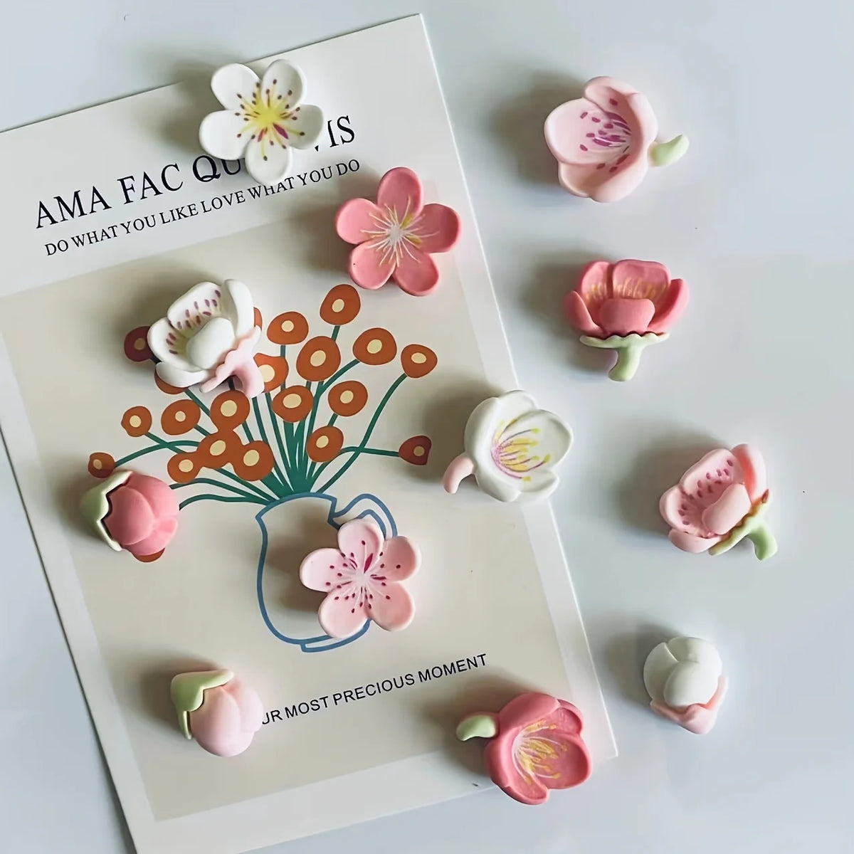 A set of 12 pink and white kawaii flower decorative fridge magnets arranged on a white card.
