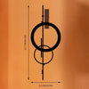Minimalistische geometrische Wandskulptur mit kreisförmigem Ring und vertikalen Linien auf orangem Hintergrund.