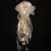 A translucent jellyfish lantern lamp with iridescent, flowing light patterns hanging against a dark background.