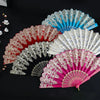 A collection of five elegant folding fans in various colors including red, pink, white, and blue, displayed on a dark surface