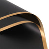 Close-up of black wrapping paper with a gold edge design, showing the texture and fold.