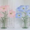A pair of large artificial silk poppy flowers in pink and blue are displayed against a white background.