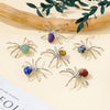 A collection of handcrafted crystal spider figurines in various colors and shades displayed on a light background.
